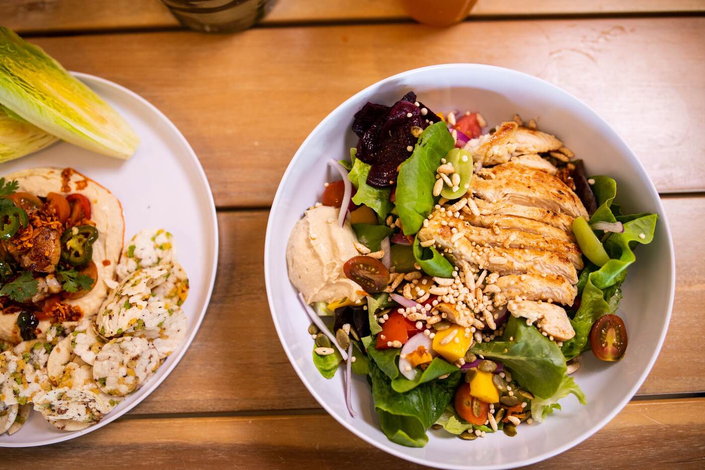 Chicken salad and hummus plates on a wood table at McFlamingo